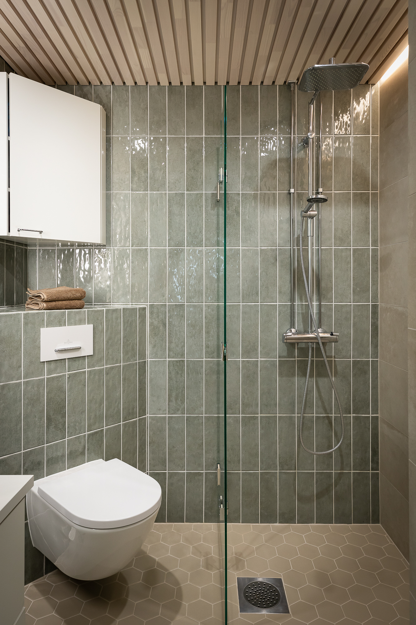 Kylpyhuone 60-luvun kerrostaloasunnossa – sisustussuunnittelu ja remontti Oulussa, vihreät laatat tuovat raikkaan värin.